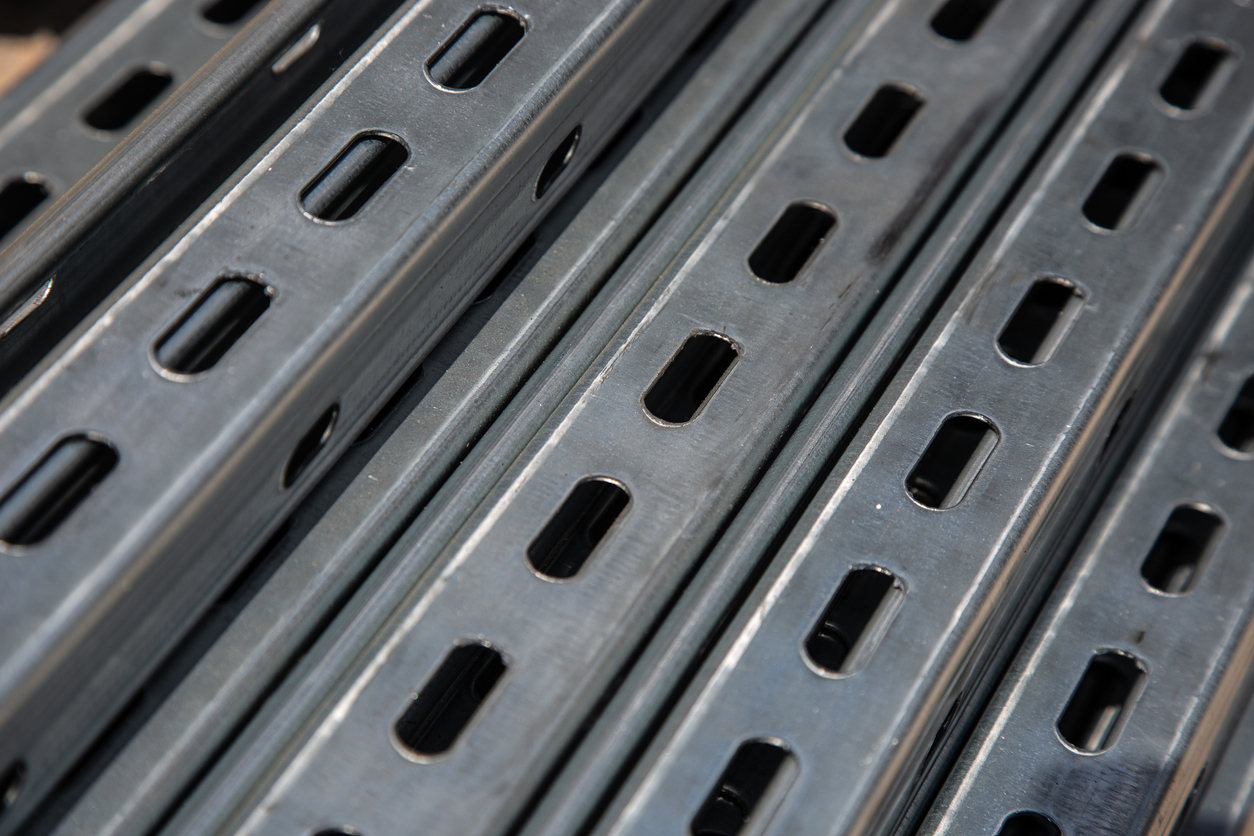Close-up of stacked galvanized metal strut channels with evenly spaced oval slots, showing industrial construction materials.